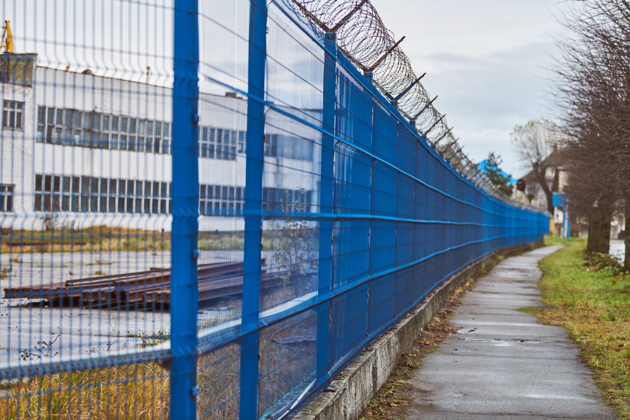 barbed wire on blue fence of restricted area