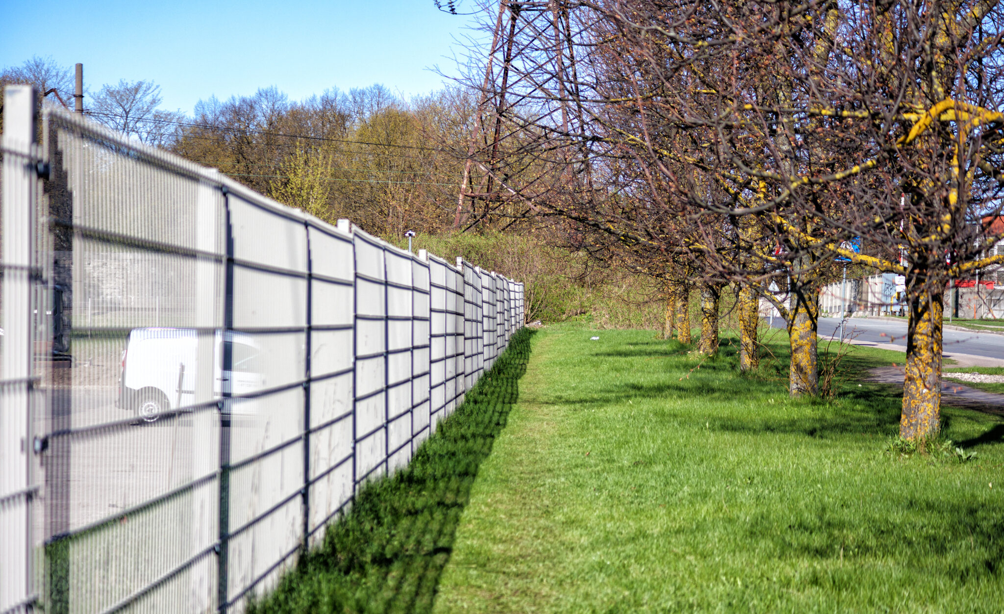 .a white fence in the garden separates the street from the green